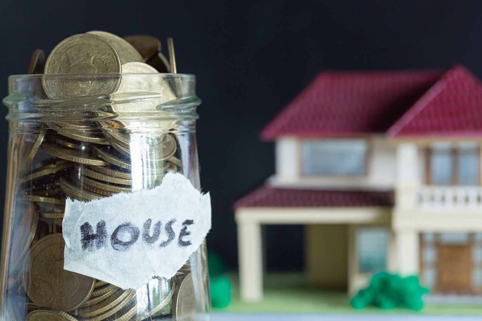 Jar of coins beside a model house representing house clearance costs