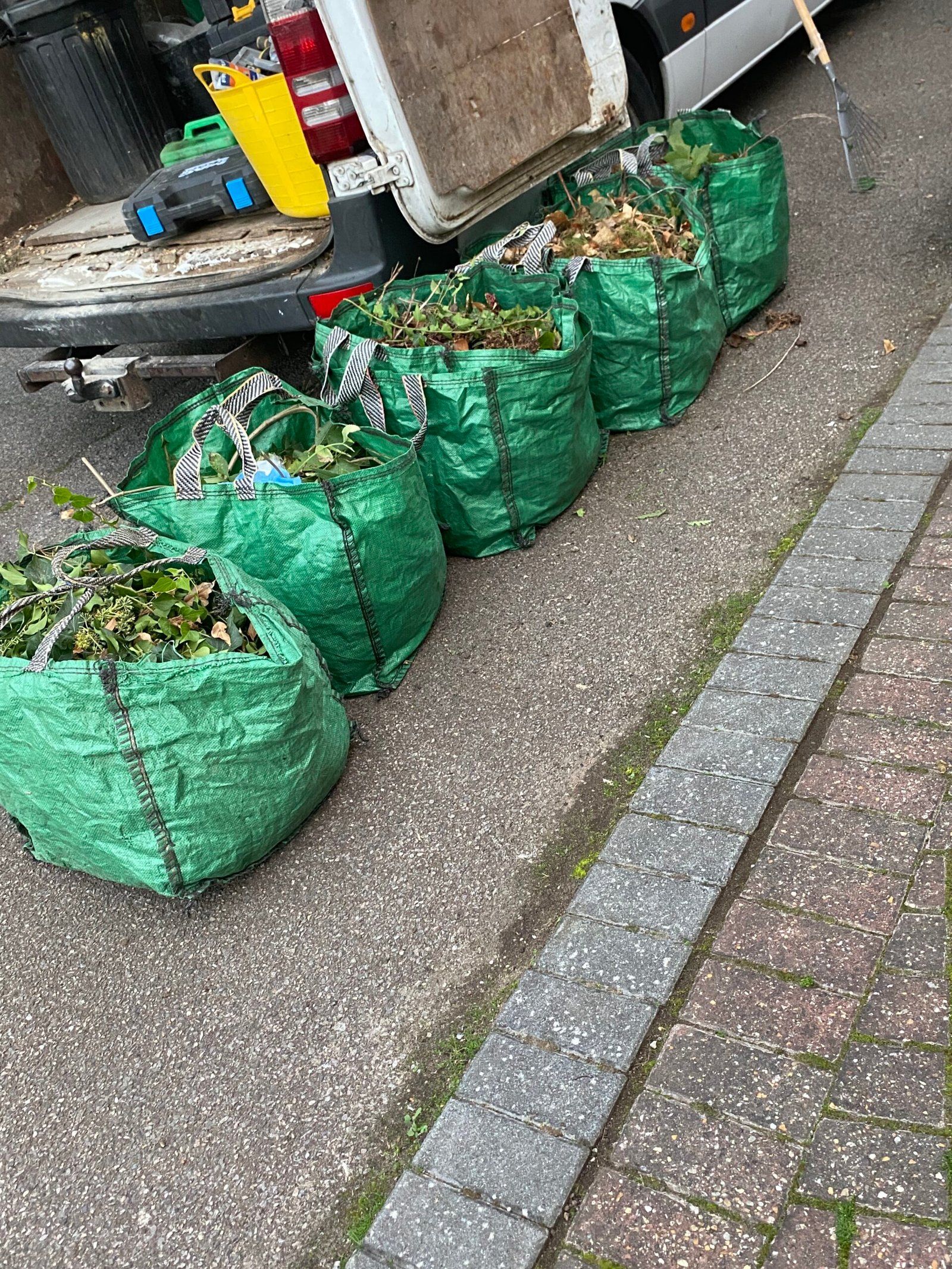 rubbish removal Basildon green bags of garden waste on a paved driveway